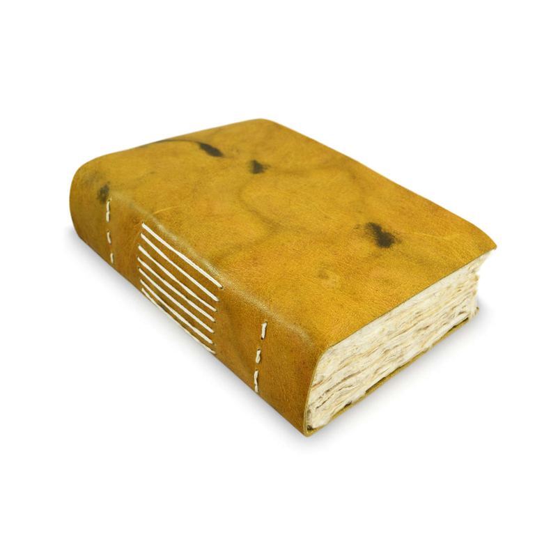 The 5 × 8 leather Nepali Yeti Tracker journal, its stitched spine and deckle-edged pages showing