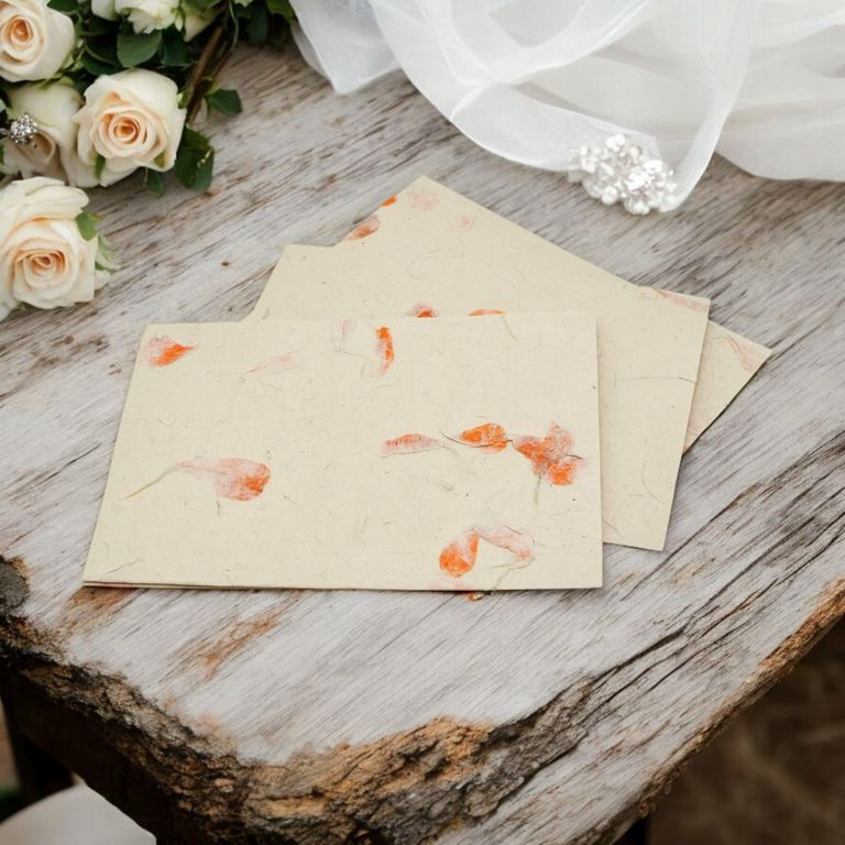 Marigold cards and envelopes on a whitewashed table beside roses