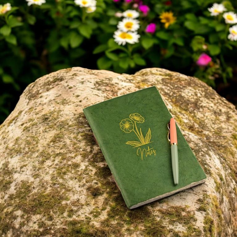 The A5 Sage Heritage Deluxe Companion notebook with a pen on a sunlit rock