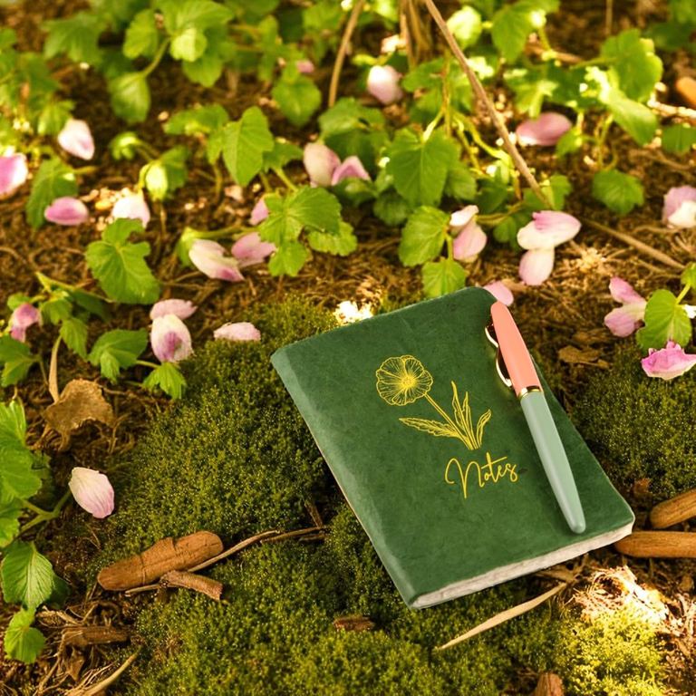 The Pocket Sage Heritage Deluxe Companion notebook with a pen on moss and clover