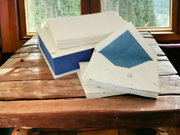 The Cornflower stationery set on a wooden table by a cabin window, pine forest and mountains outside
