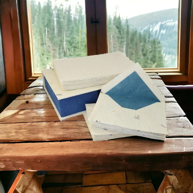A cornflower lokta stationery gift box open on a table by a window, sheets and envelopes inside