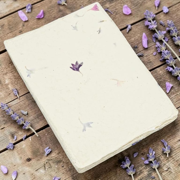 A sheet of cornflower card stock on weathered boards with sprigs of lavender and scattered petals