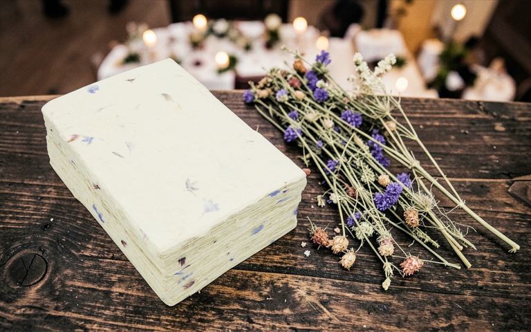 A stack of cornflower card stock on dark wood beside a bundle of dried lavender
