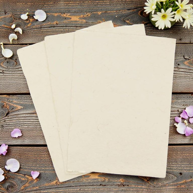 Three sheets of Deluxe washi-method 5×7 lokta card stock on dark wooden boards with daisies and petals