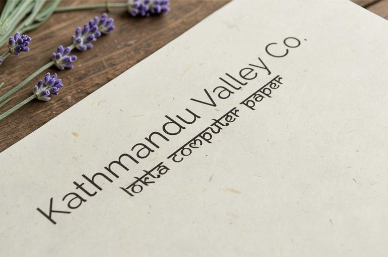 A sheet of Kathmandu Valley Co. natural lokta computer paper on a wooden table beside sprigs of lavender