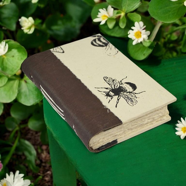 The Busy Bee Nepali Collector journal lying on a green stool among white daisies