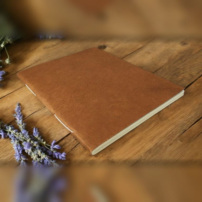 The Large Terra Cotta Nepali Companion notebook on a wooden table with lavender