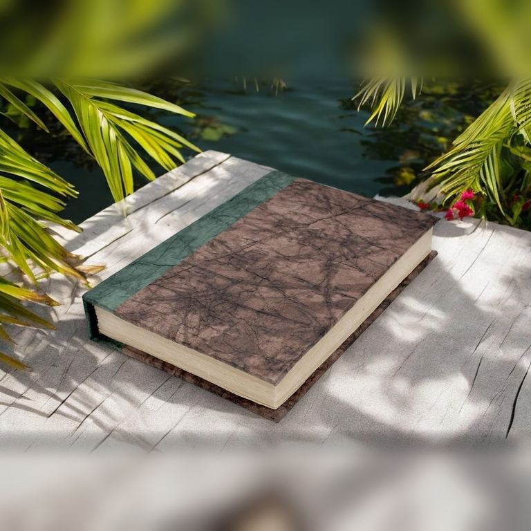The Walnut Nepali Eco journal on a sunlit white stone ledge framed by palm leaves