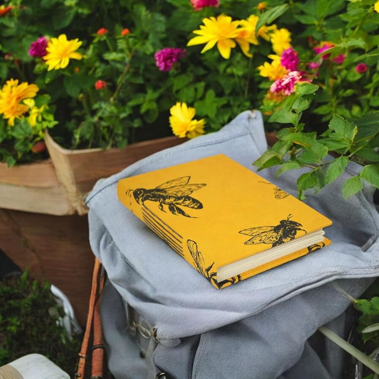 The medium Busy Bee Nepali Keeper on a canvas backpack in a flower garden