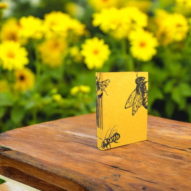 The small Busy Bee Nepali Keeper standing on a wooden table in front of yellow flowers