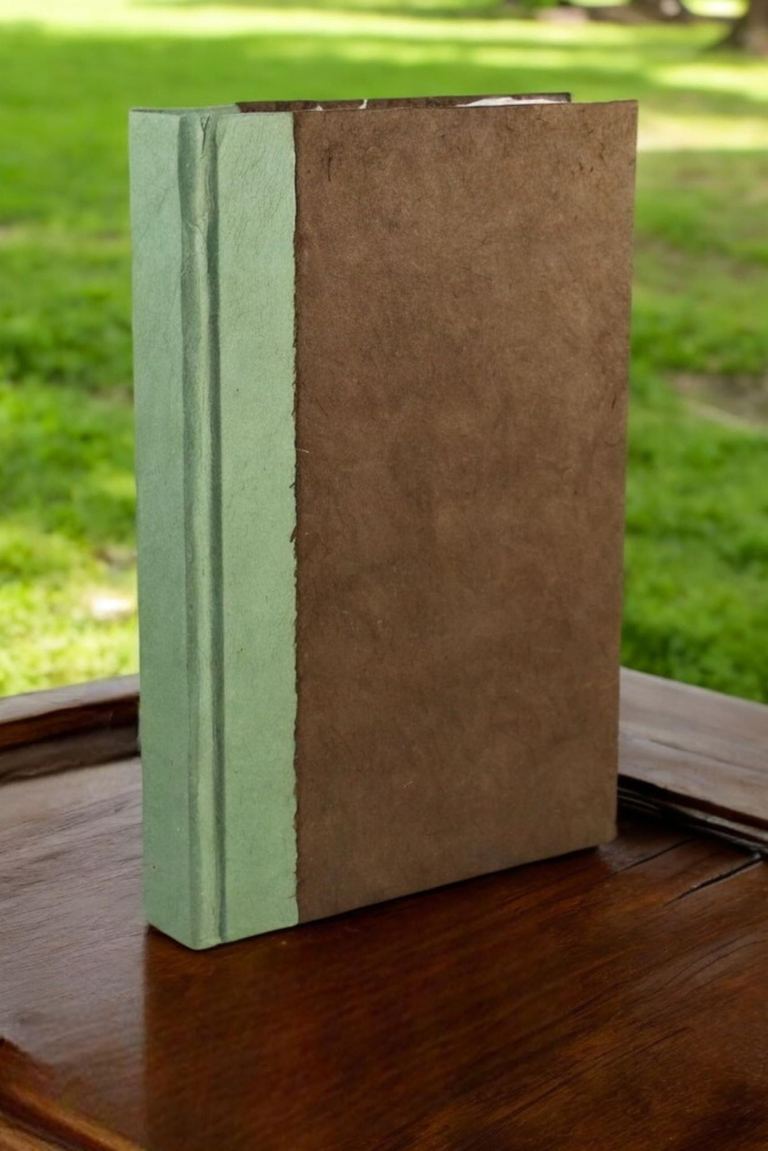 The 6 × 9 Dark Walnut Nepali Namaste journal standing on a wooden table in a sunny park