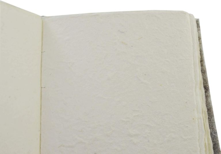 A Nepali Yeti Tracker journal open to a blank page of textured lokta, its deckled edges showing