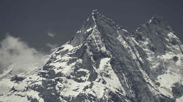 The snowy summit of Mount Khumbila against a dark sky, in black and white