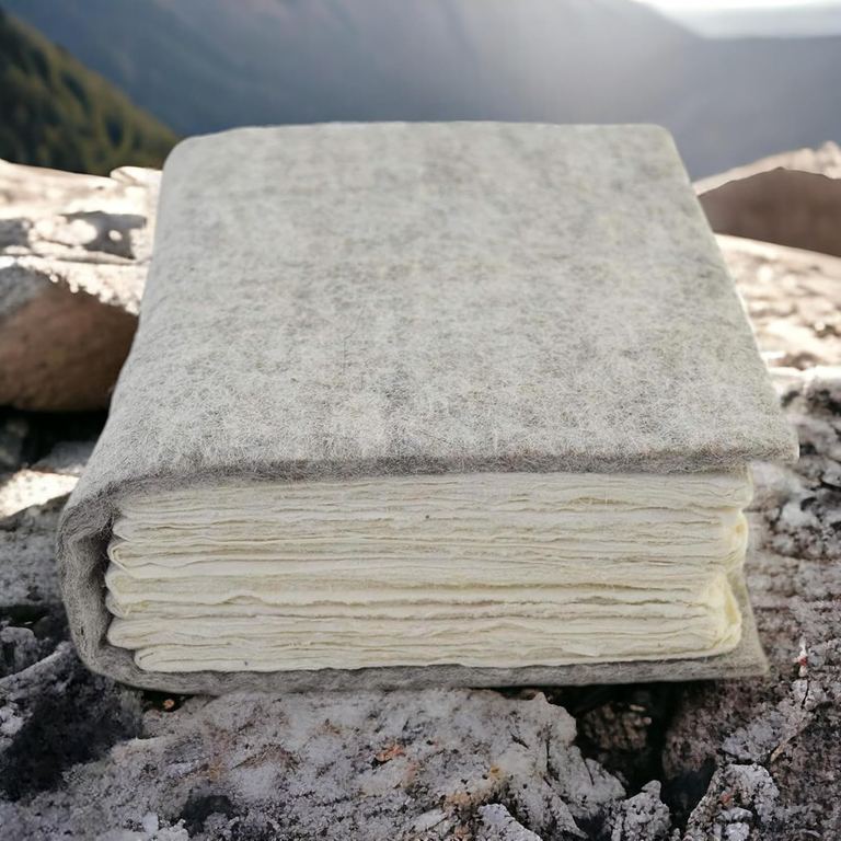 The wool felt Nepali Yeti Tracker journal on a lichen-covered rock, mountains behind