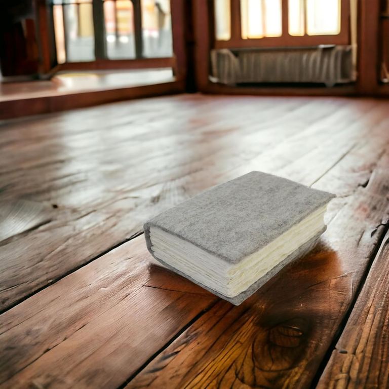 The wool felt Nepali Yeti Tracker journal on an old wooden floor in a sunlit room